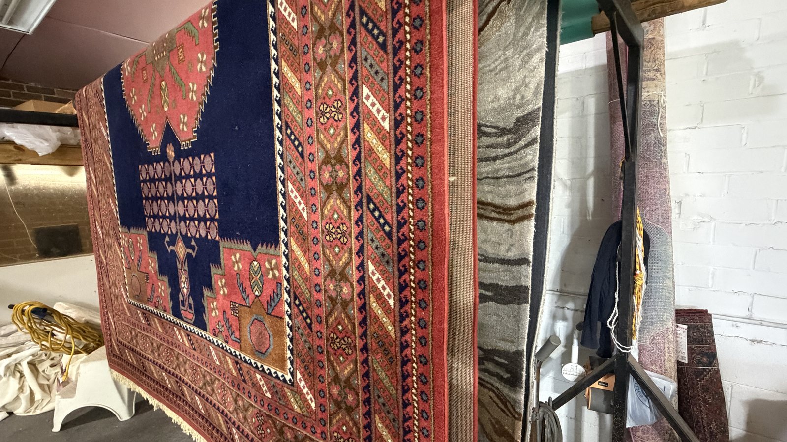 Geometric tribal rug in madder red and indigo hanging on a rack