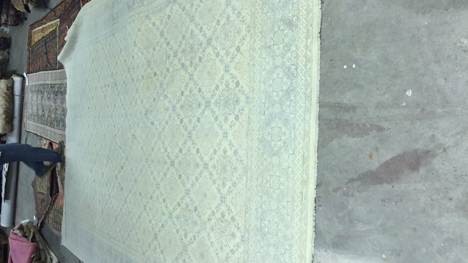 Large pale rug laid flat on the workshop floor for inspection