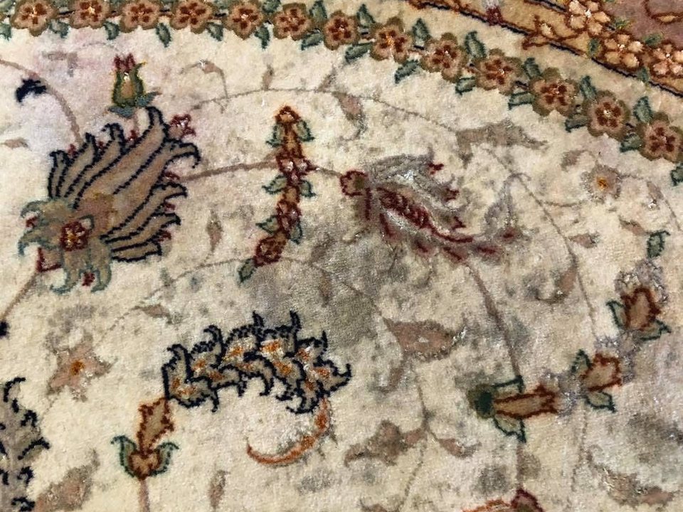 Close view of a finely knotted rug showing discolouration in the field